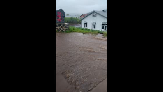 Fast-moving muddy floodwater flows downhill through residential road in Heilongjiang, China