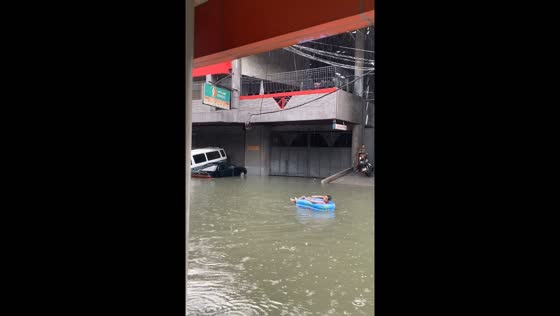 Person enjoys flood waters on inflatable raft amidst typhoon Gaemi in Quezon City, Philippines