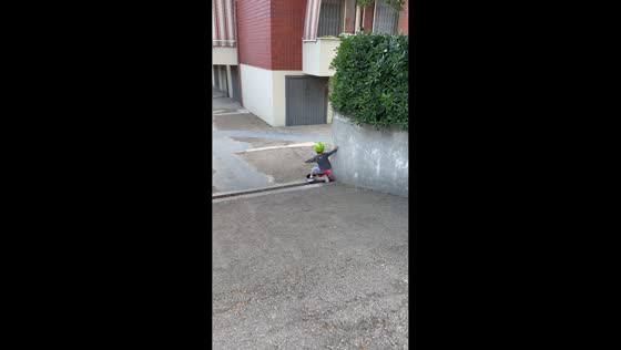 Toddler loses balance while riding toy bike downhill in Rimini. Italy