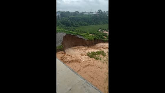 Hillside collapses as muddy floodwater rushes beneath bridge in Henan, China
