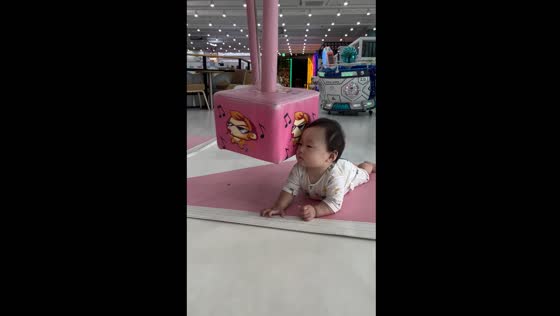 Child lays unbothered as plush toys spin by