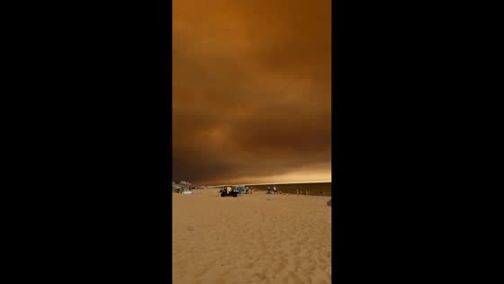People remain on Lacanau Ocean shoreline under gloomy skies in New Aquitaine, France