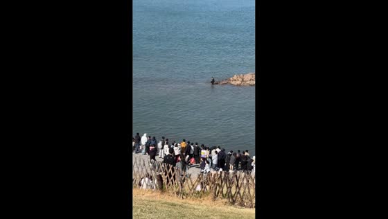 Man carefully walks from sea rock back to shore in Jiangsu, China