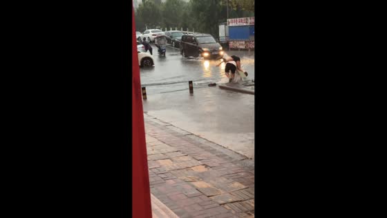 Couple slips and falls crossing flooded road in Anhui, China