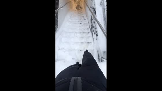 Man slips down snow-covered stairs in Queens, New York, USA