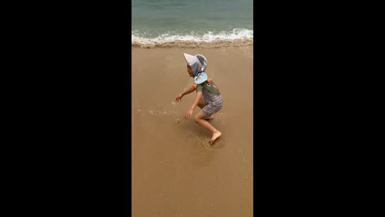 Boy tumbles onto sand after ocean wave hits his feet in Jiangsu, China