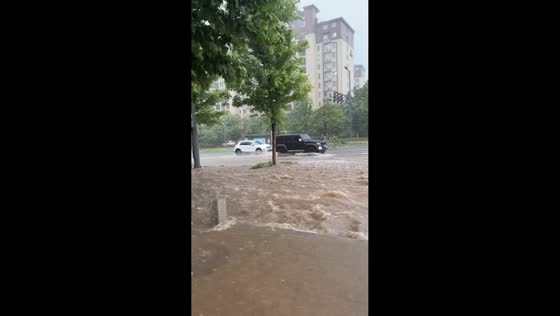 Motorcyclist falls while navigating flooded intersection in Henan, China