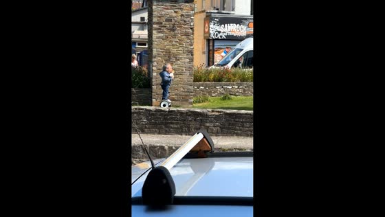 Warwick Davis rides segway while eating ice cream in Perranporth, England, UK