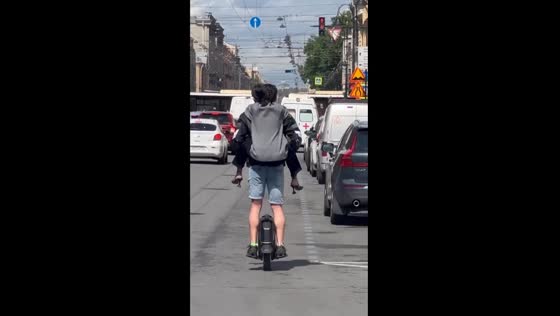 Two daredevils navigate St. Petersburg traffic on tandem one-wheel scooter