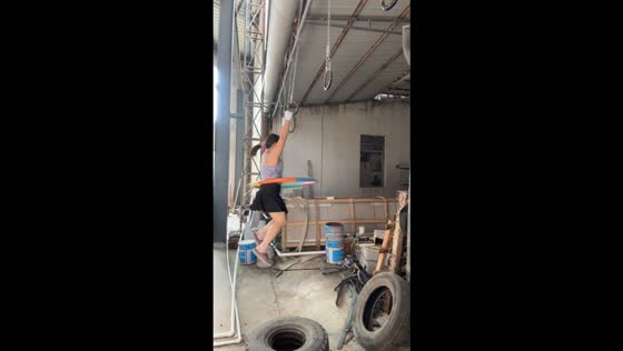 Woman spins a hula hoop while hanging from gymnastic rings in Shantou, China