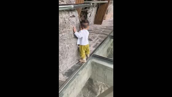 Boy cautiously avoids the glass walkway by sticking to the stone path in Hubei, China