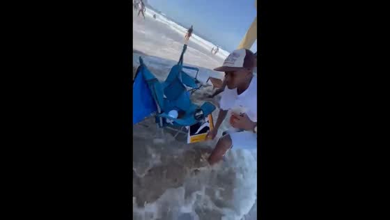 Wave washes away food while friends drink in Durban, South Africa