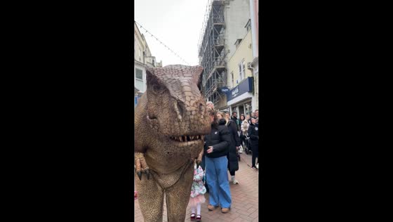 Dinosaur mascot playfully startles passerby in Weymouth, England, UK