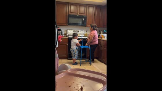 Boy helps flatten tortilla using automated press in in Oxnard, California, USA