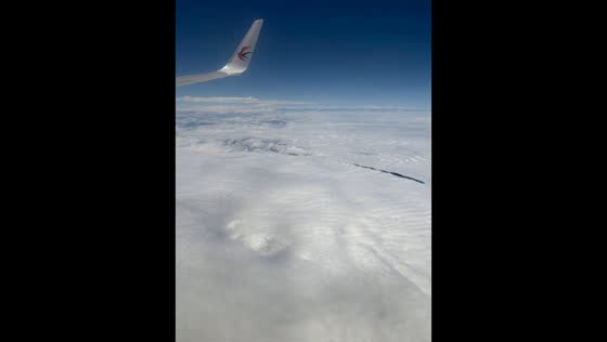 Cloud tops ripple like waves beneath passenger jet over Kunming, China