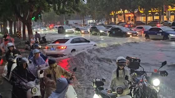 Vehicles navigate fast-moving floodwaters on busy road in Jinan, China