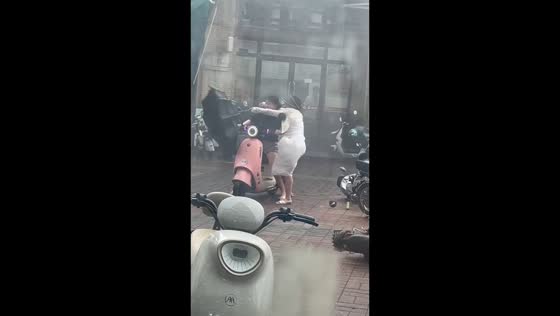 Woman struggles with umbrella as powerful winds hit during typhoon in Guangdong, China