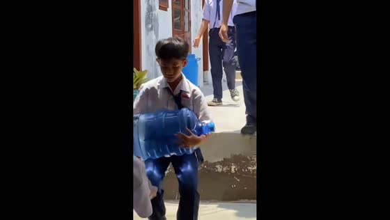  Student trips while carrying a gallon of water in Lampung, Indonesia