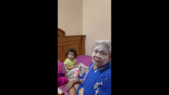 Great-grandmother plays with baby covered in powder in Palembang, Indonesia
