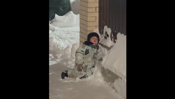 Child falls asleep on snow while father clears nearby area in Kazan, Russia