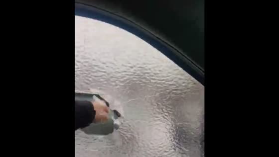 Punching a frozen car window to clear ice obstruction