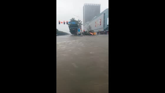 Vehicle passes through murky floodwaters covering multi-lane road in Henan, China