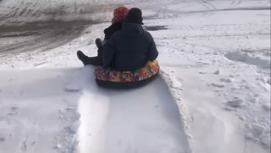 Two men enjoy playful tire sledding in heavy snow in Heilongjiang, China