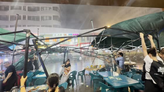 Sudden rainstorm sends diners scrambling at outdoor seafood stall in Qingdao, Shandong, China