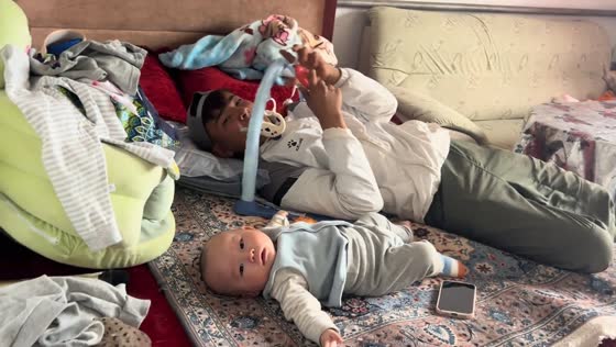 Uncle playfully swaps places with baby on play mat in Xinjiang, China