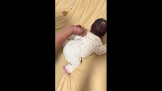 Baby reacts adorably to gentle tickling on bed in Anhui, China