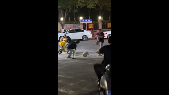 Man spins and strikes ball bollard during nighttime street moment in Guangxi, China