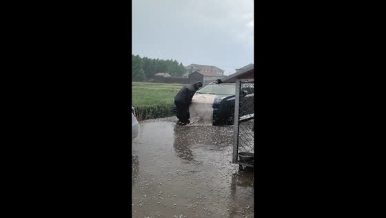 Man struggles to cover car during hailstorm in Jiangsu, China
