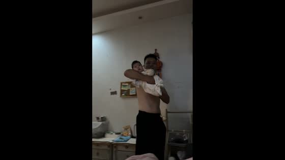 Father playfully marches around room while carrying baby in Henan, China