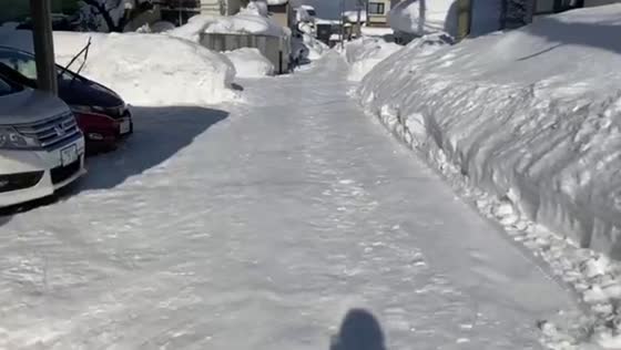 Drivers navigate streets with towering snow walls in Aomori, Japan