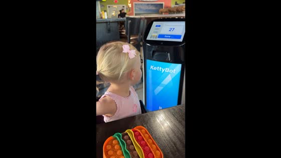 Little girl amazed by robot server in Panama City Beach, Florida, USA