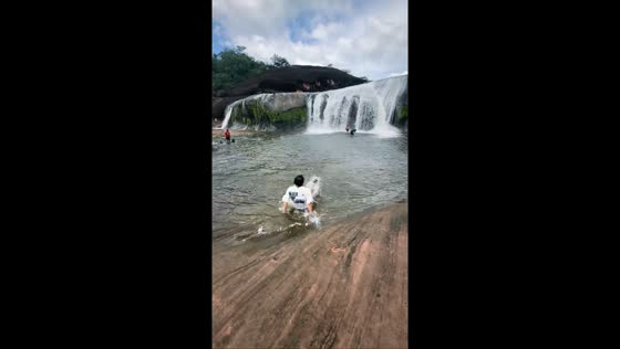 Man slips while posing at Tham Phra Waterfall in Bueng Kan, Thailand