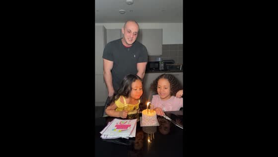 Sisterly teamwork: birthday girl gets help blowing out candles