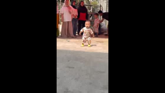 Toddler dances with funny expressions while people watch in West Bandung, Indonesia