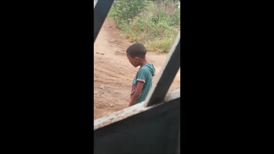 Child playfully mimics rooster in Feira de Santana, Bahia