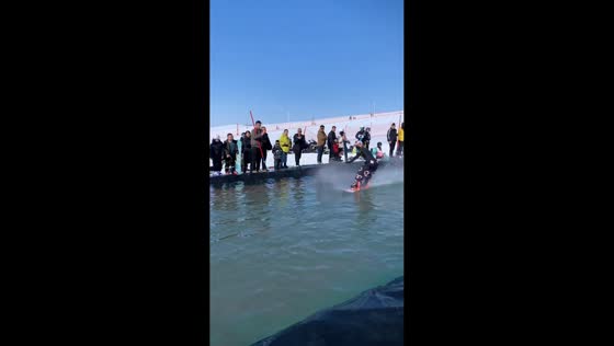 Woman skillfully crosses water obstacle on snowboard in Gansu, China