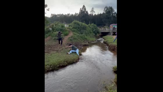 Person jumps over river but falls, getting muddy, in Tamil Nadu, India