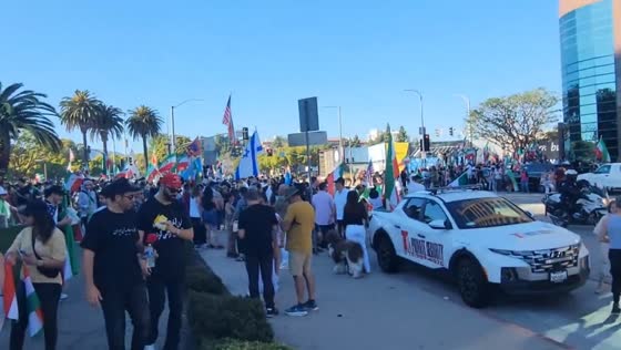 Helicopter flies over flag-waving crowd near Wilshire Boulevard in Los Angeles, California, USA