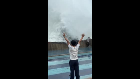 Large wave drenches people along coastal promenade in Shandong, China
