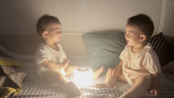 Two toddlers laugh while playing with a lamp in Guangdong, China