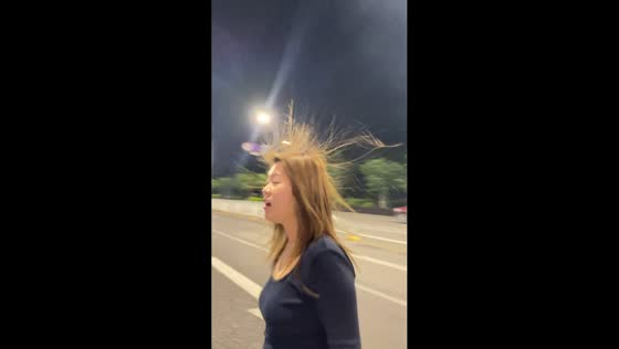 Woman’s hair stands up while walking on road in Zhejiang, China