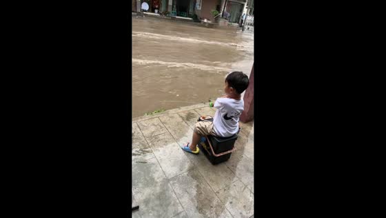 Child tries fishing in flooded street in Guizhou, China