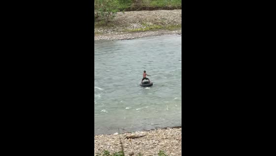 Little boy surfs on swim tube in river in Paya Bakong, North Aceh, Indonesia