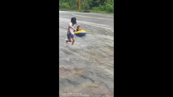 Children enjoy flooded street with inflatable boat during rainstorm in Guizhou, China