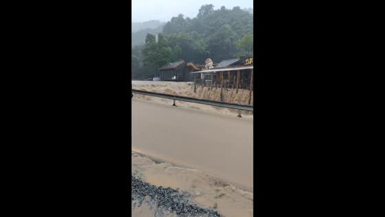 Turbulent river overflows onto road and surrounding area in Cangnan, China