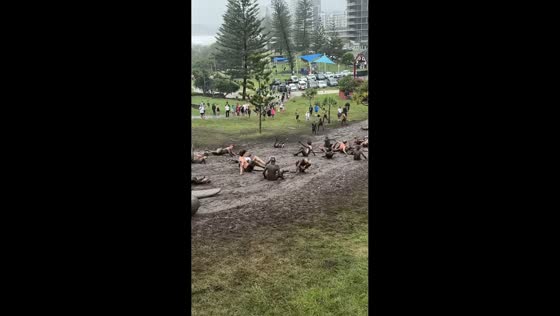 People ride boards down muddy slope in Gold Coast, Australia